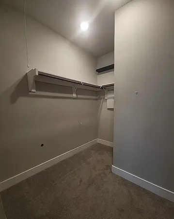 an empty room with a fan & a window