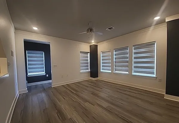 an empty room with wooden floor and windows
