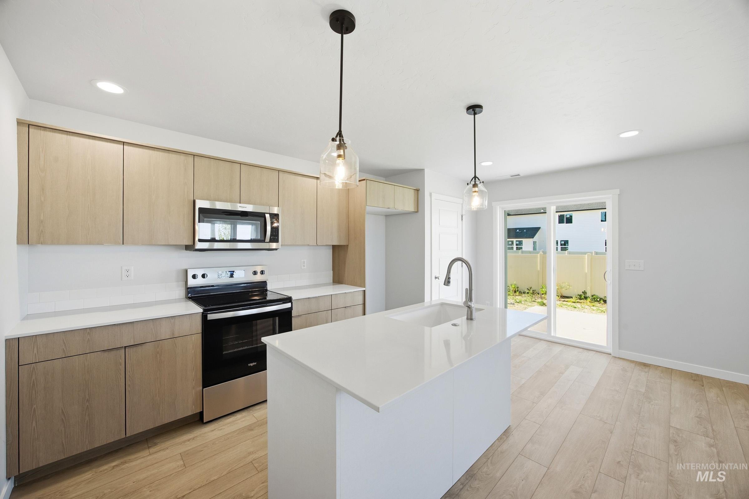 16211 Andes Avenue Caldwell, ID 83607 - Photo 5 of 22 Kitchen featuring light wood-finish cabinetry, stainless steel appliances, a center island with an integrated sink, and recessed lighting