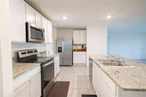 a kitchen with granite countertop a sink dishwasher stove and oven with wooden floor