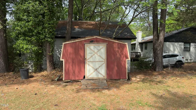 a view of backyard with a barn and large trees