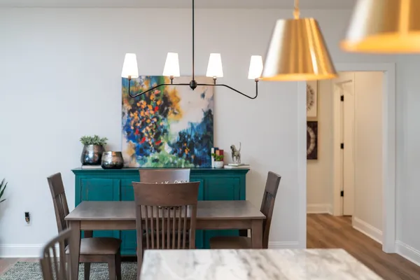 a kitchen with stainless steel appliances granite countertop a stove top oven a sink a dining table and chairs with wooden floor