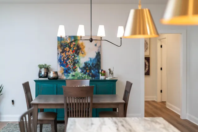 a kitchen with stainless steel appliances granite countertop a stove top oven a sink a dining table and chairs with wooden floor