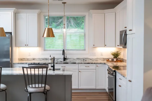 a kitchen with granite countertop a stove and white cabinets