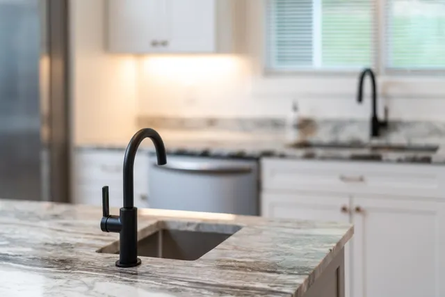 a kitchen with kitchen island granite countertop a sink a stove and a microwave
