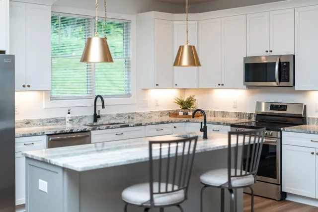 a kitchen with granite countertop white cabinets and stainless steel appliances