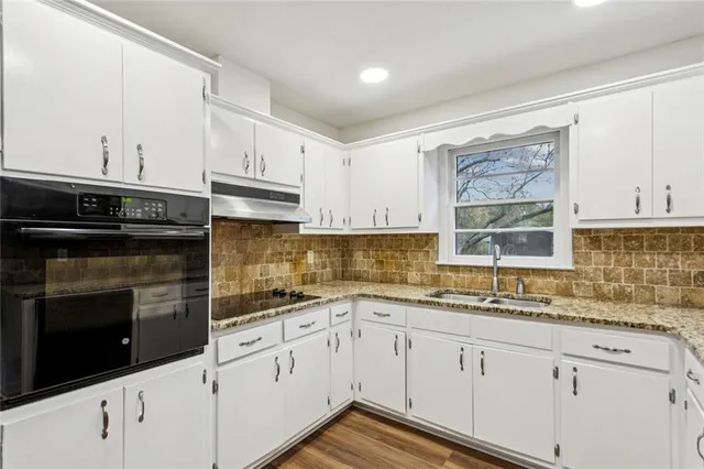 a kitchen with granite countertop white cabinets white stainless steel appliances and a sink