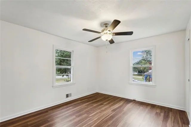 a view of an empty room with a window and wooden floor
