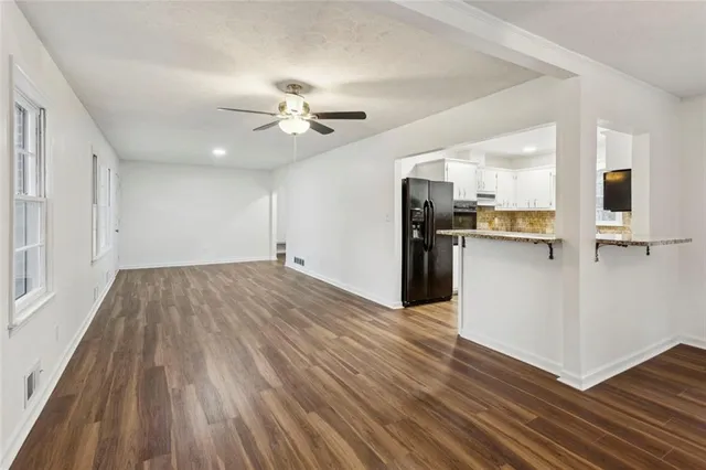 a view of a kitchen with wooden floor a sink a refrigerator and window