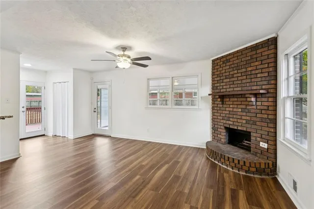 a view of a livingroom with wooden floor a ceiling fan and windows