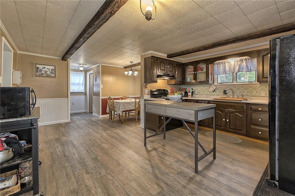 3456 Country Club Road Mount Pleasant, PA 15666 - Photo 17 of 39 a dining hall with stainless steel appliances granite countertop a stove a sink dishwasher and a dining table with wooden floor
