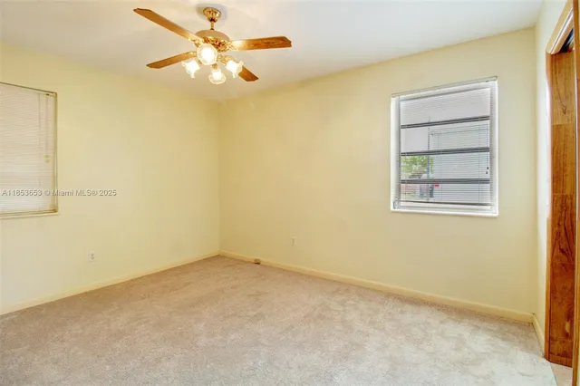 an empty room with a window and a ceiling fan