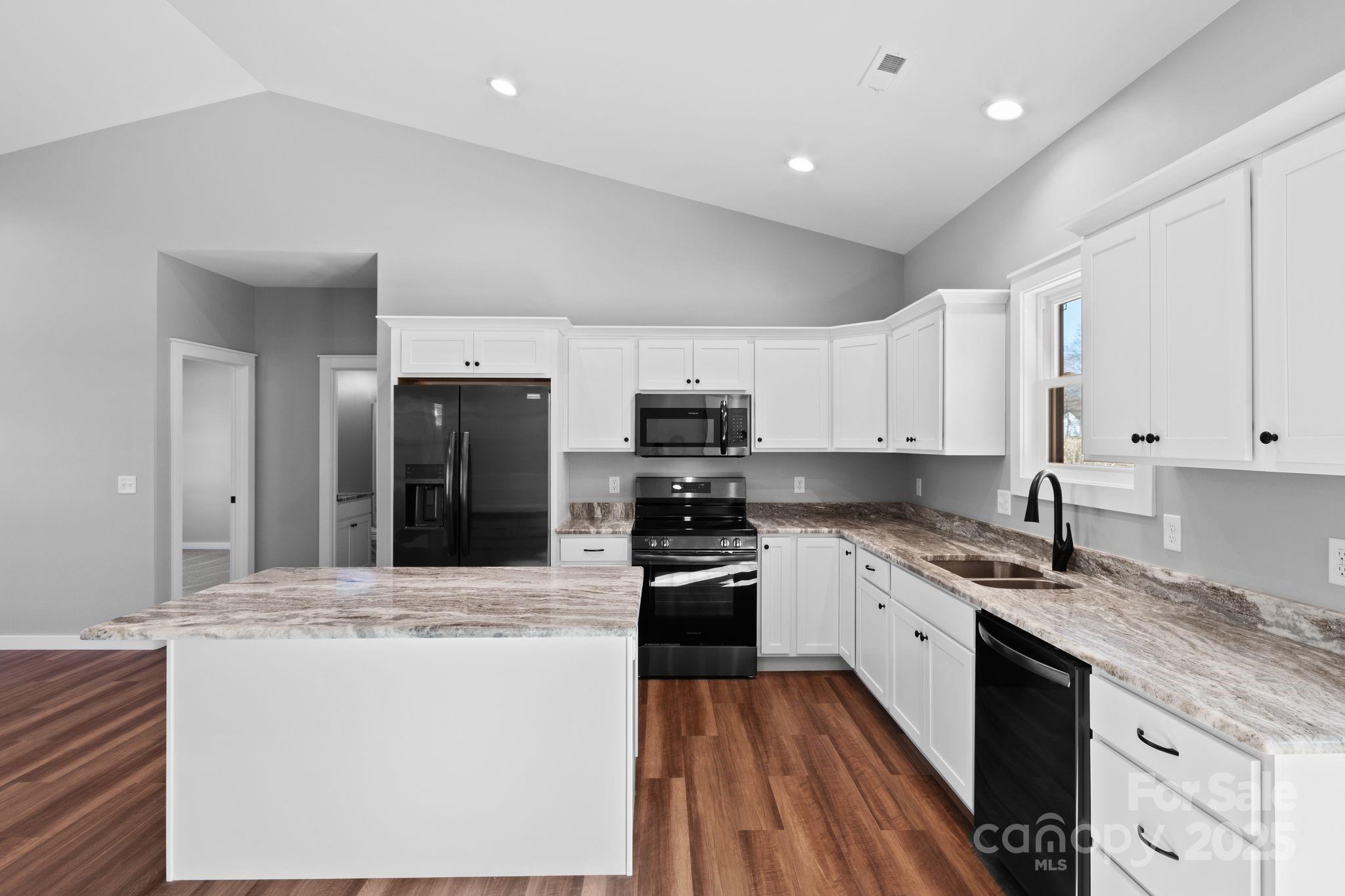 80 Peyton Elaine Road Clyde, NC 28721 - Photo 6 of 28 a kitchen with stainless steel appliances granite countertop a stove top oven a sink a refrigerator and white cabinets with wooden floor