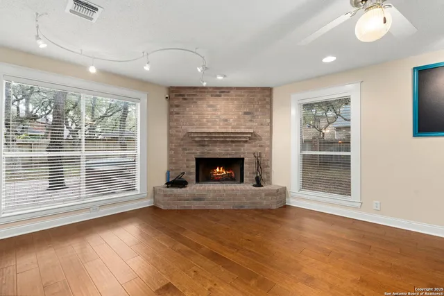 a view of an empty room with wooden floor fireplace and a window