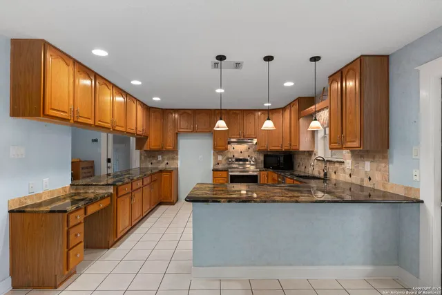 a kitchen with stainless steel appliances granite countertop a sink a stove and a refrigerator