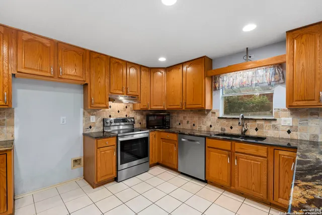 a kitchen with stainless steel appliances granite countertop stove top oven a sink dishwasher and a refrigerator