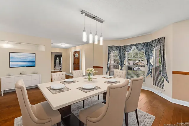 a dining room with furniture a large window and wooden floor