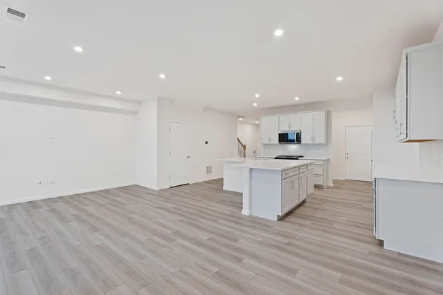 a large kitchen with a center island wooden floor and a sink
