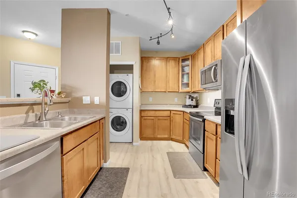 a kitchen with stainless steel appliances granite countertop a refrigerator a sink dishwasher a stove and a dining table with wooden floor