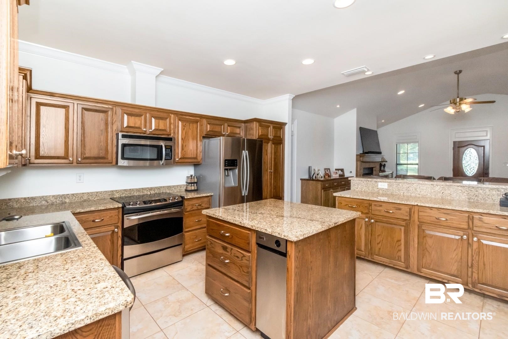 1360 Dykes Road North Mobile, AL 36608 - Photo 10 of 40 Kitchen with brown cabinetry, a kitchen island, lofted ceiling, appliances with stainless steel finishes, and light stone countertops