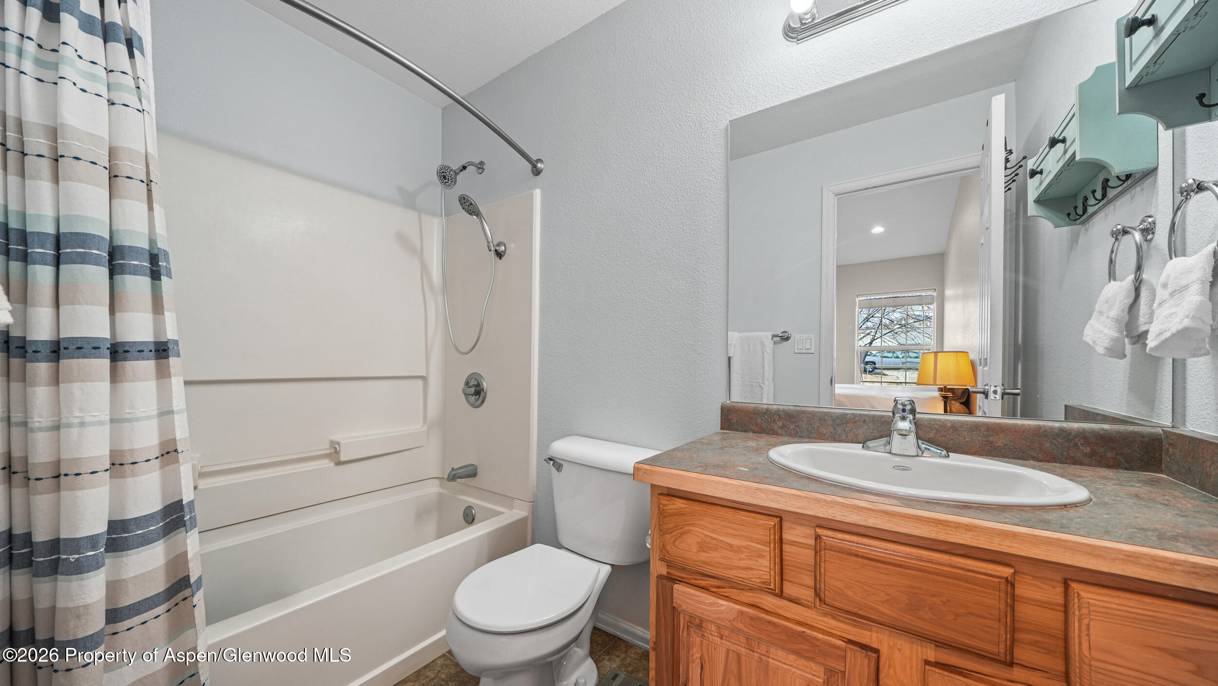 2703 Acacia Court Rifle, CO 81650 - Photo 15 of 29 a bathroom with a granite countertop sink toilet a shower a mirror and shower