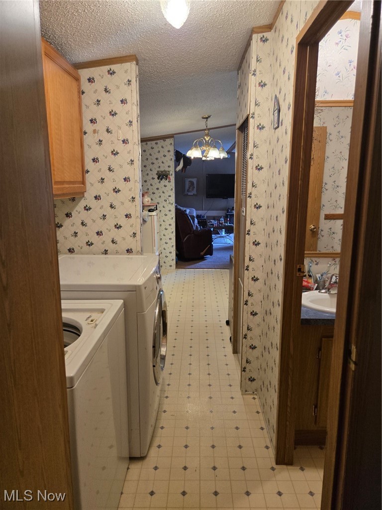 5974 Cleveland Road, Unit 23 Wooster, OH 44691 - Photo 21 of 29 Washroom with a chandelier, wallpapered walls, a textured ceiling, washing machine and dryer, and cabinet space
