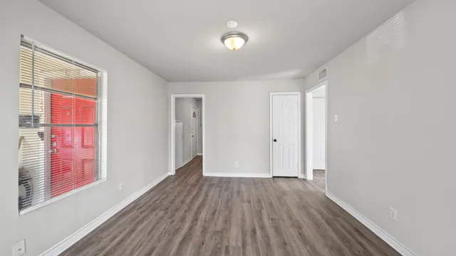 a view of an empty room with wooden floor and a window