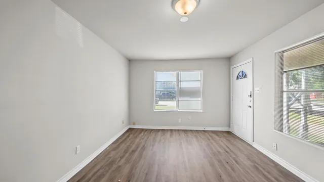 an empty room with wooden floor and windows