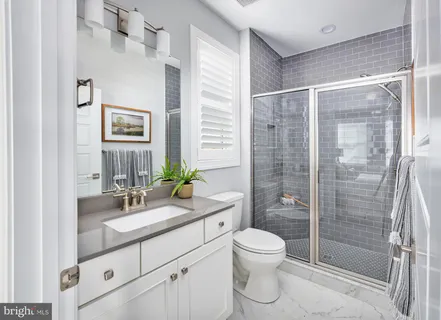 a bathroom with a shower sink vanity mirror and toilet