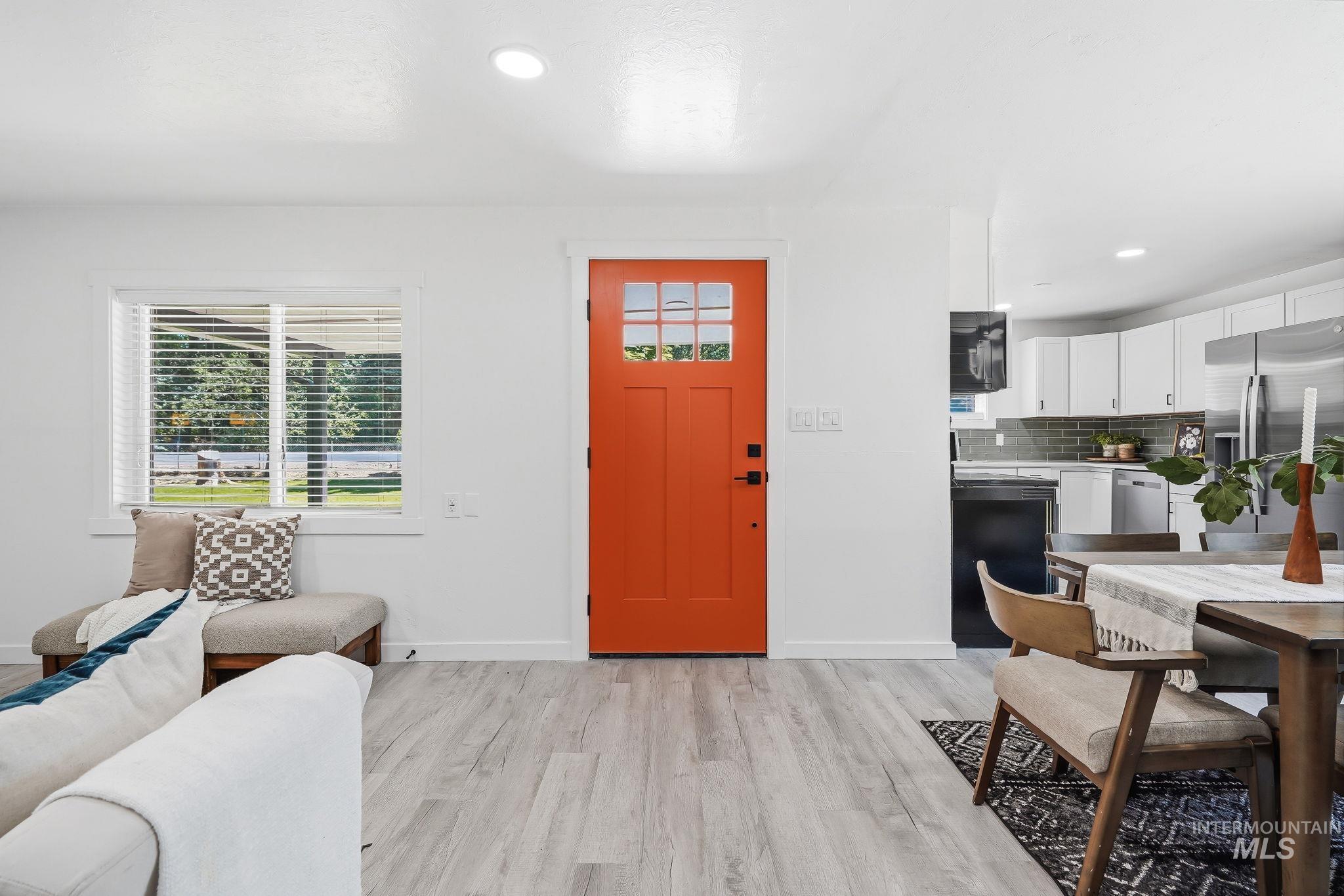 2152 Artesian Road Eagle, ID 83616 - Photo 7 of 50 Vibrant orange front door with glass panels, light wood-finish flooring, recessed lighting, white walls, and a window showcasing outdoor greenery