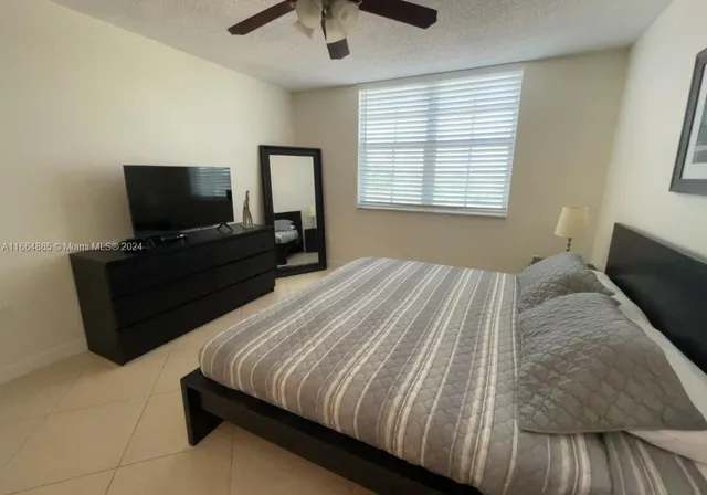 a bedroom with a bed and a flat tv screen on dresser