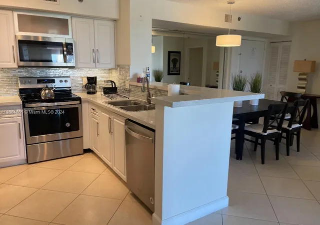 a kitchen with stainless steel appliances granite countertop a stove top oven a sink a dining table and chairs