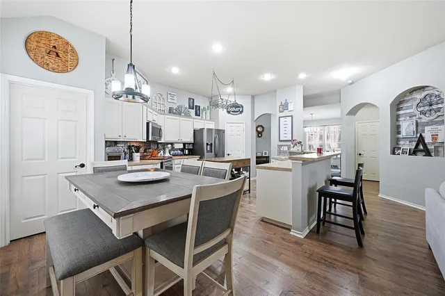 a kitchen with a dining table chairs cabinets and wooden floor