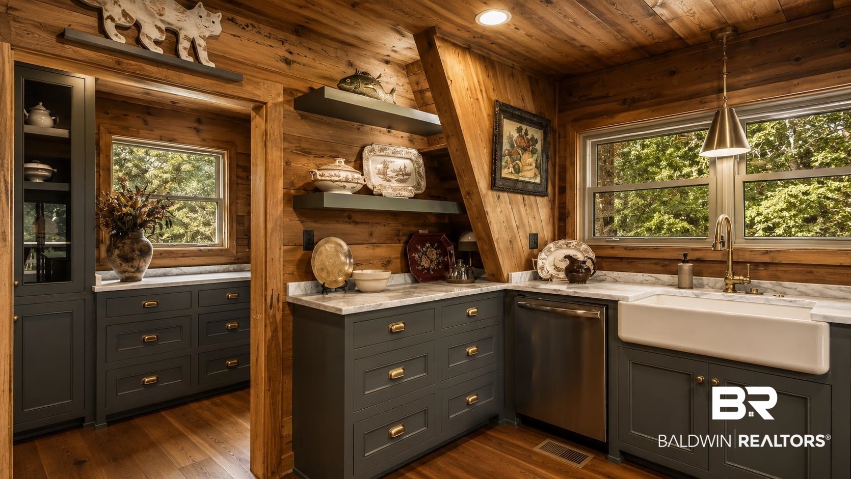 14587 Ridge Road Summerdale, AL 36580 - Photo 14 of 44 Kitchen featuring wood-paneled walls and ceiling, dark gray cabinetry with brass hardware, light-toned countertops, a white farmhouse sink with a brass faucet, and multiple windows