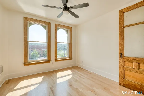 a view of an empty room with a window and wooden floor