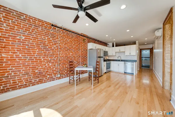 a view of kitchen with stainless steel appliances wooden floor dining table and chairs
