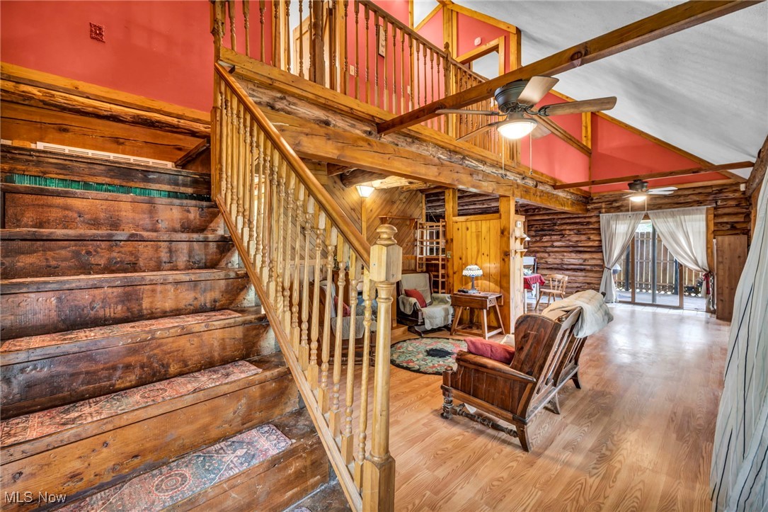 24455 Tryon Road Oakwood, OH 44146 - Photo 31 of 40 Stairs with beam ceiling, rustic walls, wood finished floors, ceiling fan, and high vaulted ceiling