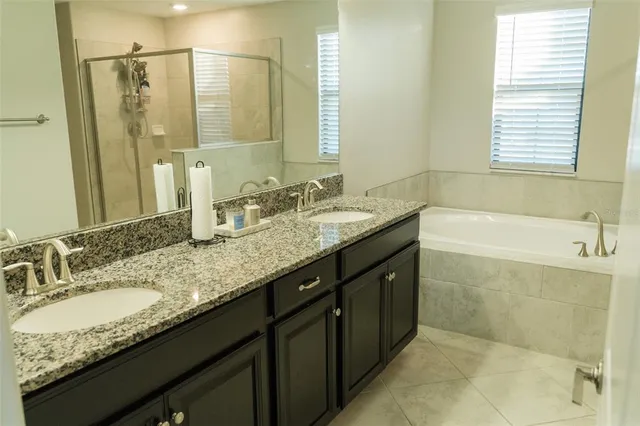 a bathroom with a granite countertop bathtub sink vanity and mirror