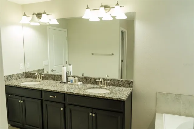 a bathroom with a granite countertop double vanity sink and a mirror