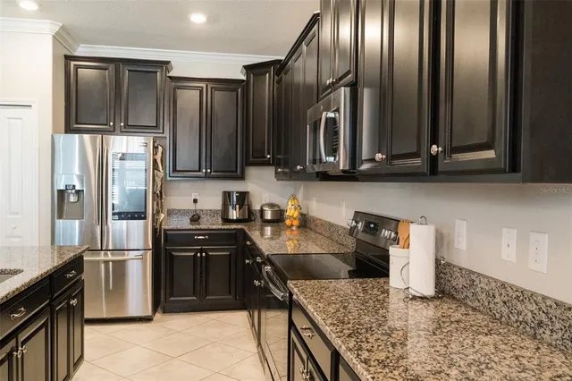 a kitchen with granite countertop stainless steel appliances a refrigerator stove top oven and sink
