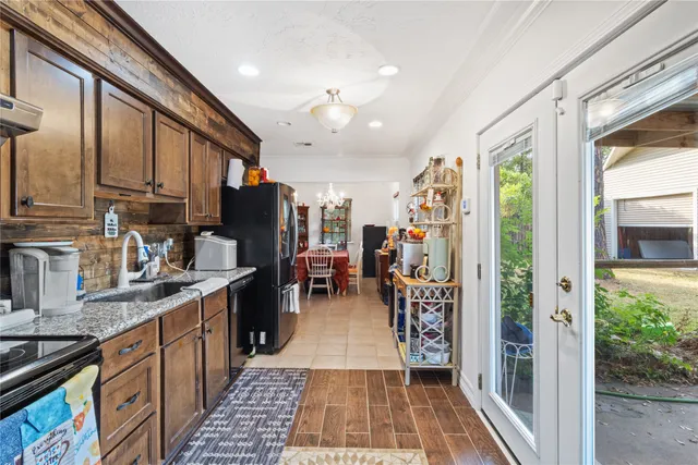 a kitchen with stainless steel appliances granite countertop a refrigerator a sink dishwasher a stove and a dining table with wooden floor