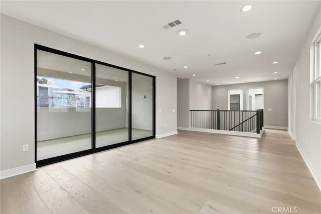 a view of an empty room with wooden floor and a glass door