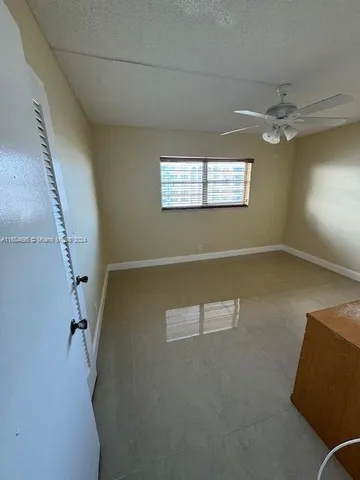 an empty room with windows and ceiling fan