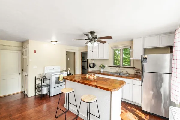 a kitchen with stainless steel appliances granite countertop a refrigerator a stove a sink dishwasher and a dining table with wooden floor