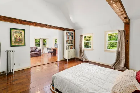 a bedroom with wooden floor and windows