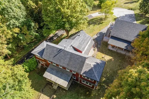 an aerial view of a house with a yard and trees all around