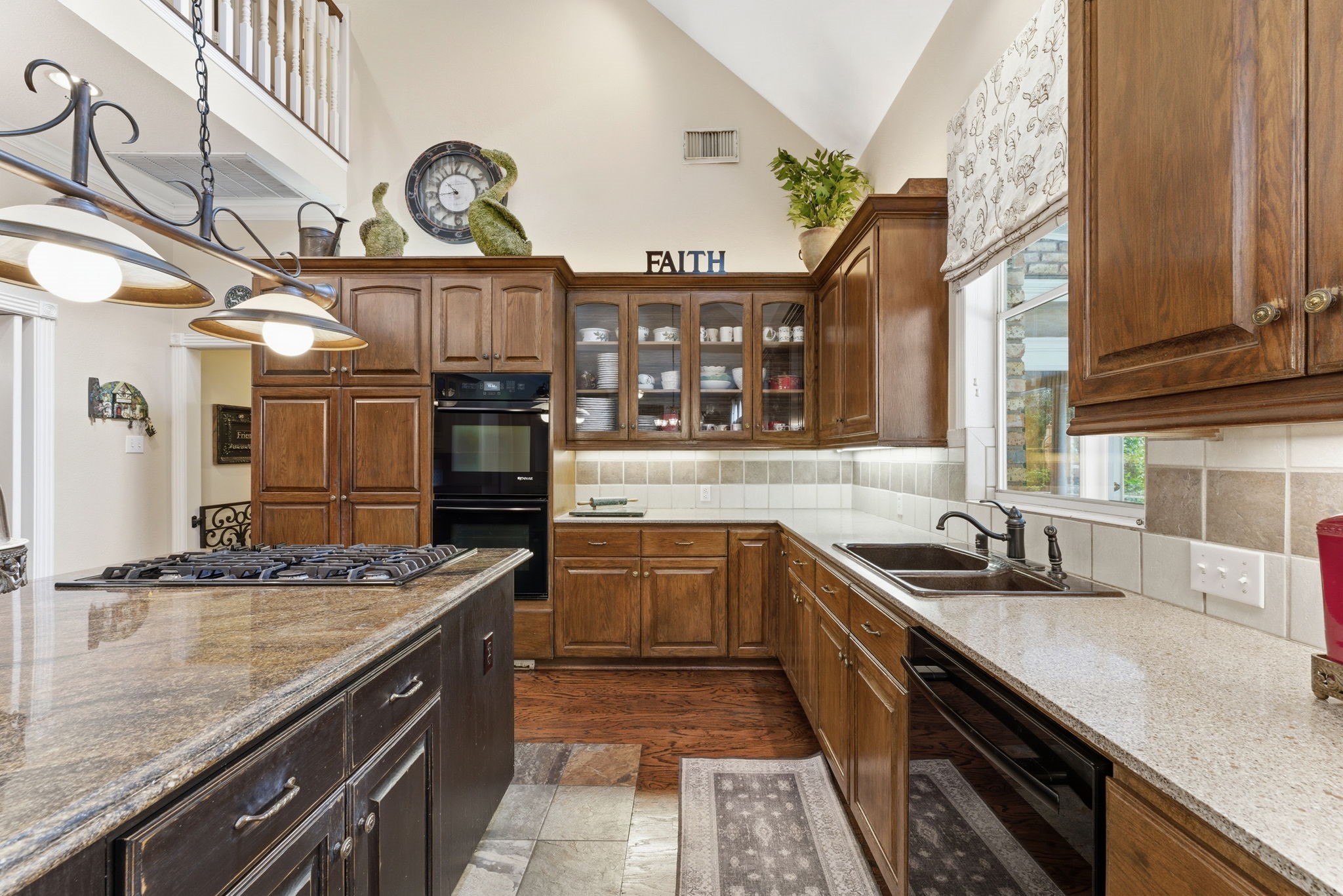 147 North Taylor Point Drive Spring, TX 77382 - Photo 16 of 44 Discover a captivating kitchen boasting high vaulted ceilings, elegant dark wood cabinetry, and sleek granite countertops, perfect for culinary enthusiasts and entertainers alike.