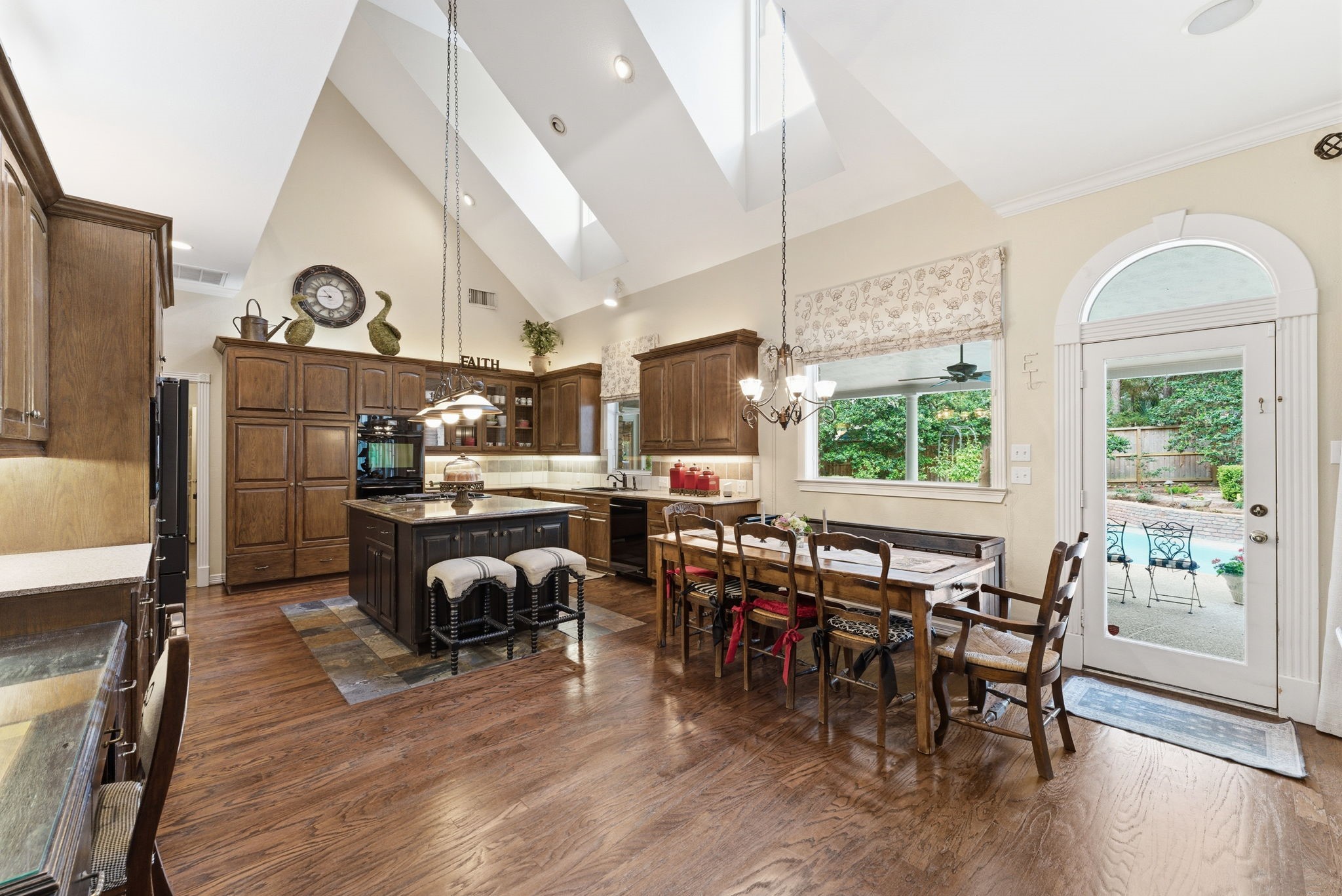 147 North Taylor Point Drive Spring, TX 77382 - Photo 18 of 44 This inviting kitchen and dining area boasts vaulted ceilings with skylights, rich wood cabinetry, and a spacious layout perfect for entertaining, all leading to a serene outdoor patio through elegant French doors.