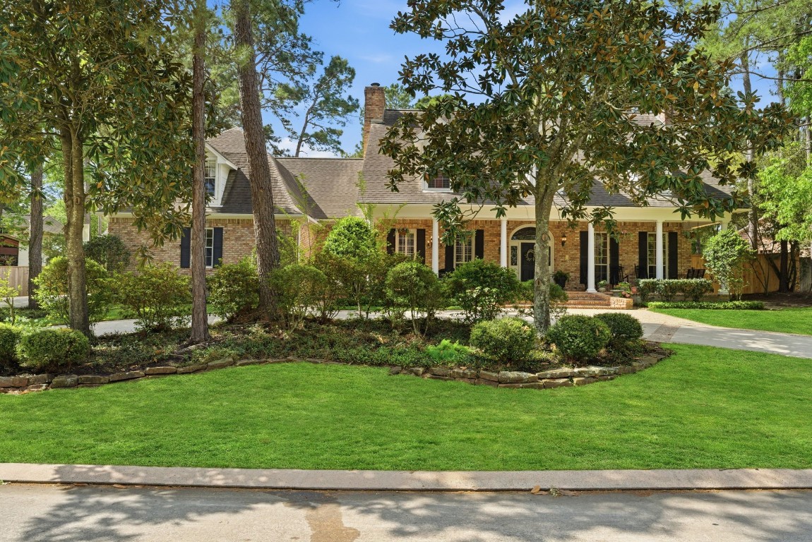 147 North Taylor Point Drive Spring, TX 77382 - Photo 2 of 44 This captivating home boasts charming curb appeal, nestled among mature trees with a beautifully landscaped front yard, leading to a welcoming brick facade that invites you to explore further.
