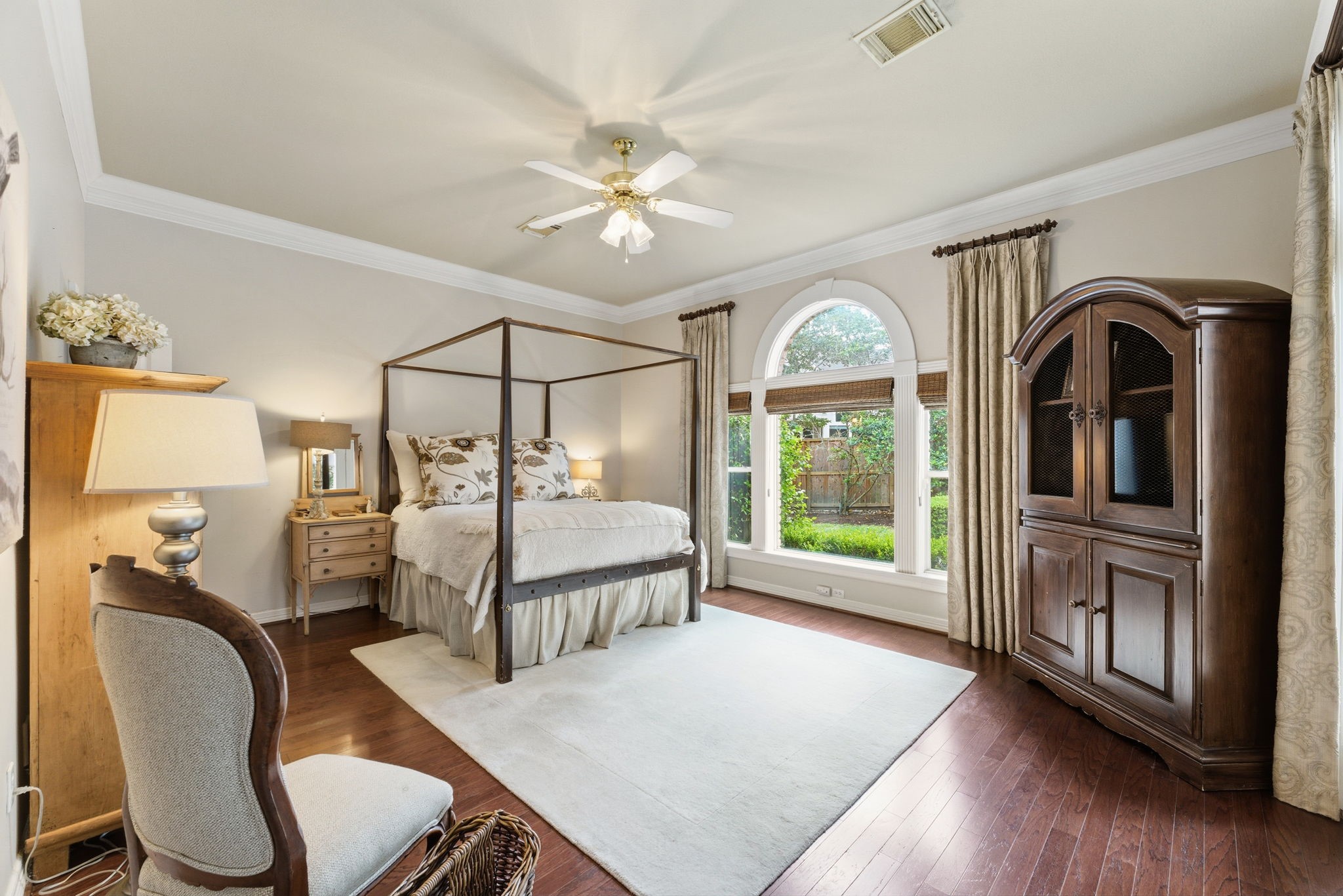 147 North Taylor Point Drive Spring, TX 77382 - Photo 21 of 44 This inviting primary bedroom offers a quiet retreat with its elegant four-poster bed, warm hardwood floors, and abundant natural light streaming through large windows that overlook the lush garden, creating a perfect blend of comfort and style.